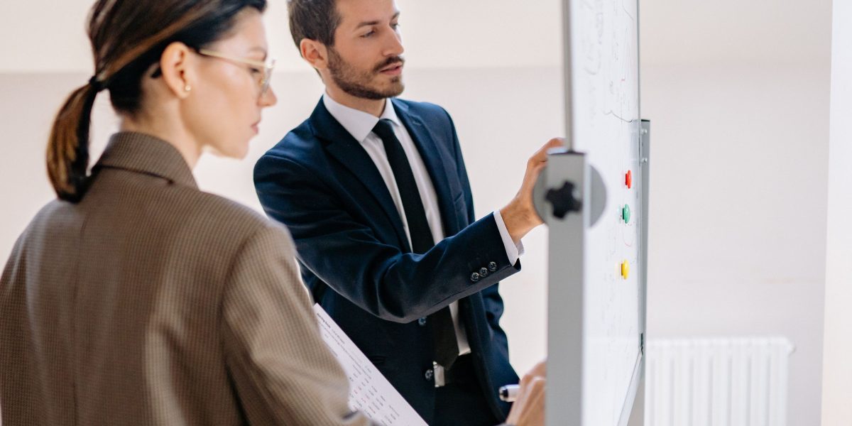 A team actively discussing their strategy around a whiteboard, aiming to close their precision gap.