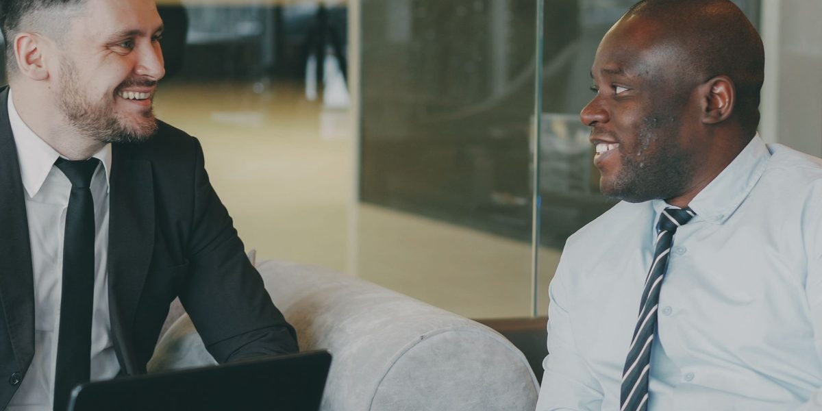 An experienced professional offering guidance to a younger individual at an alumni networking event.