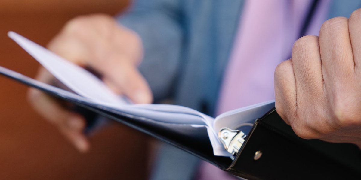 A person meticulously organizes printed reports and data sheets, a key step in data cleaning and analysis.